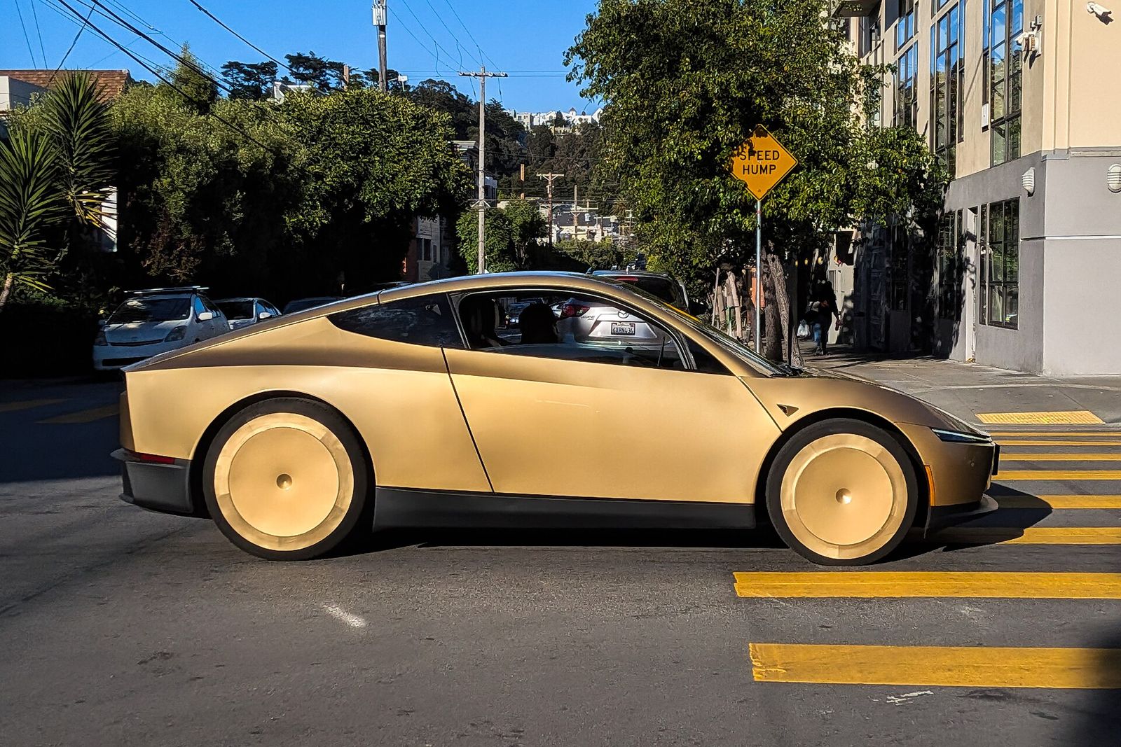 A gold Tesla Cybercab driving down Harrison Street in San Francisco